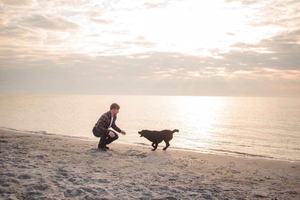 beginningstreatment-alternative-recovery-therapies-article-photo-young-man-having-fun-with-dog-on-the-morning-beach-622963610