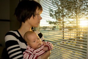 beginningstreatment-five-hurdles-keeping-single-parents-stuck-in-a-cycle-of-addiction-photo-young-mother-looking-out-from-the-window-with-her-baby-12774499