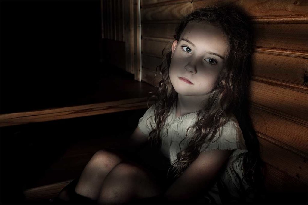 beginningstreatment-how-childhood-trauma-creates-adult-addicts-article-photo-depressed-girl-sitting-in-a-dark-hallway-in-home-321259787