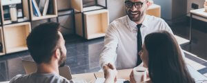 beginningstreatment-paying-for-rehab-photo-sealing-a-deal-top-view-of-two-men-sitting-at-the-desk-and-shaking-hands-while-young-woman-looking-431846332