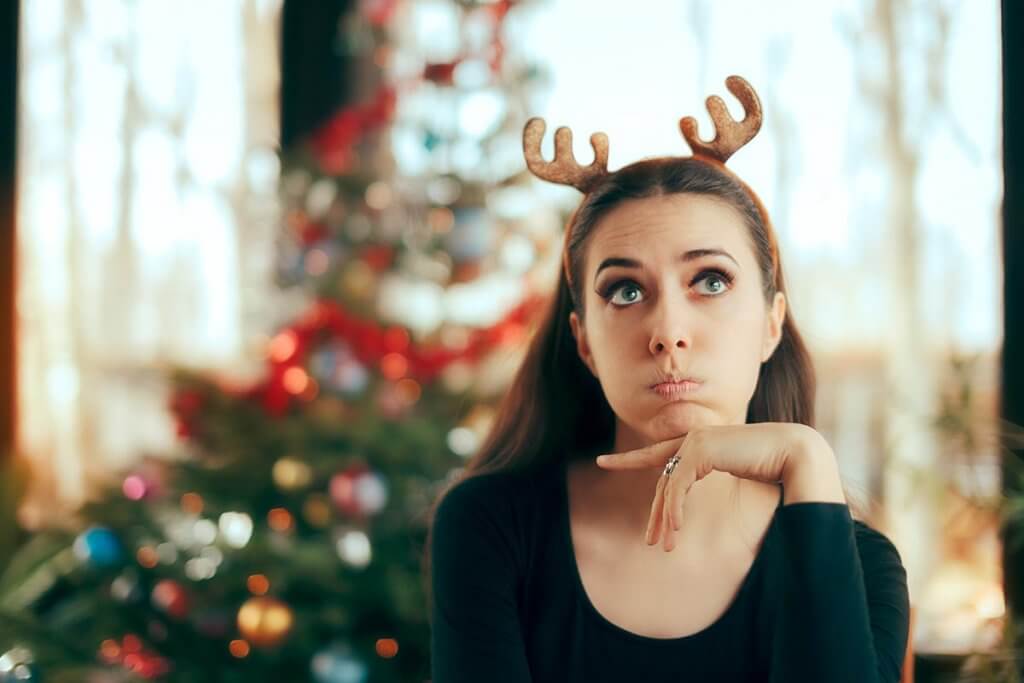 beginningstreatment-how-to-maintain-your-sobriety-over-the-holidays-article-photo-sad-bored-woman-having-no-fun-at-christmas-dinner-party-funny-girl-wearing-reindeer-horns-741241924