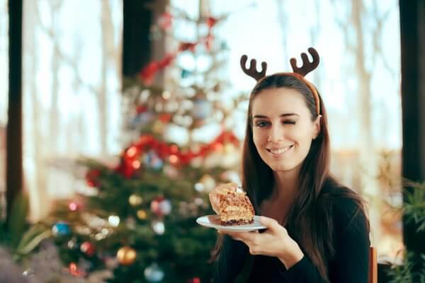 beginningstreatmentim-alone-can-i-stay-sober-over-the-holidays-article-photo-happy-woman-eating-cake-at-christmas-dinner-party-smiling-girl-eating-dessert-at-xmas-festivity-741241867