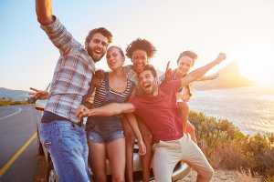 beginningstreatment-7-tips-for-a-successful-sober-vacation-article-photo-group-of-friends-standing-by-car-on-coastal-road-at-sunset