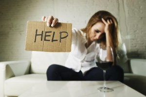 beginningstreatment-how-to-stay-in-recovery-if-you-work-around-alcohol-article-photo-of-a-woman-drinking-whiskey-glass-asking-for-help-holding-message-board-depressed