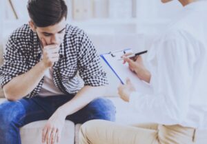 Doctor taking notes while talking to man