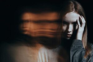 Woman holding her head while experiencing delusions