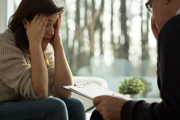 Woman crying while talking to her drug rehabilitation doctor