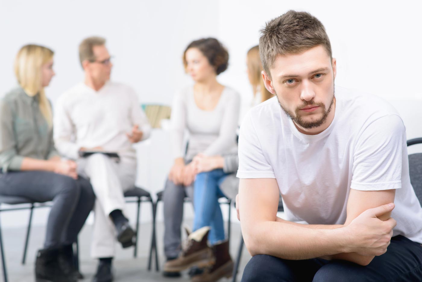 photo of man looking disinterested in talking with group