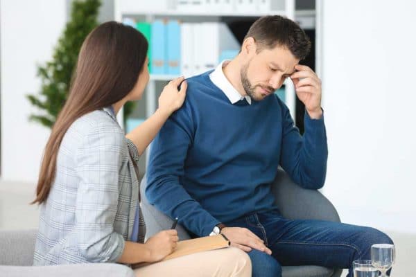 Man being comforted by his doctor while recovering in drug addiction treatment.