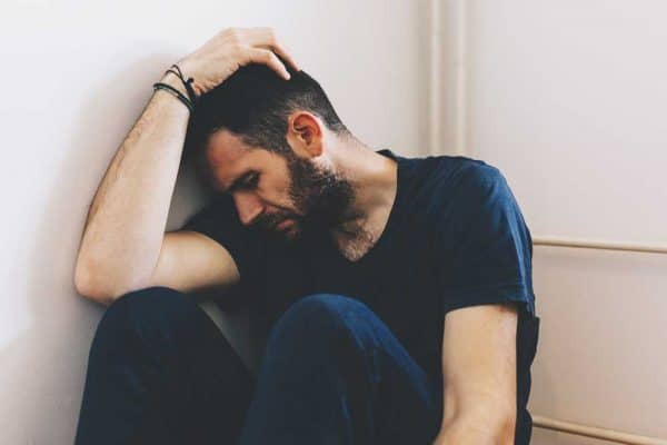 Man sitting next to a wall thinking if he should go to rehab