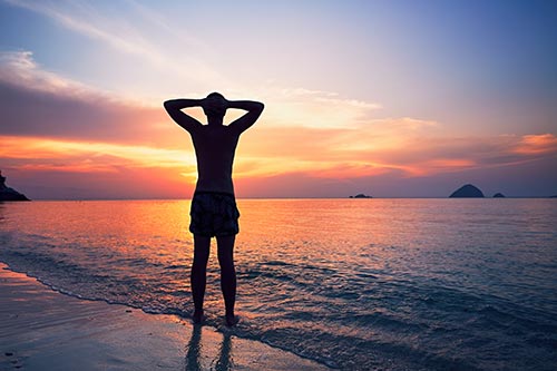 Person standing on beach watching the sunset