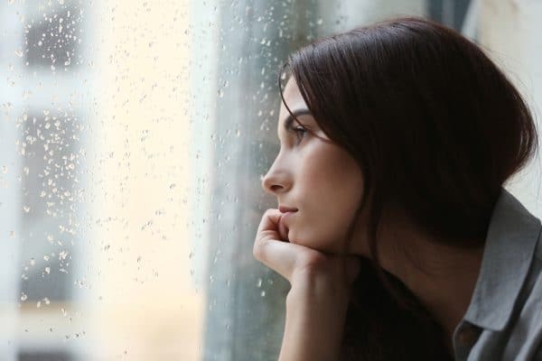 Woman looking out a window while it is raining